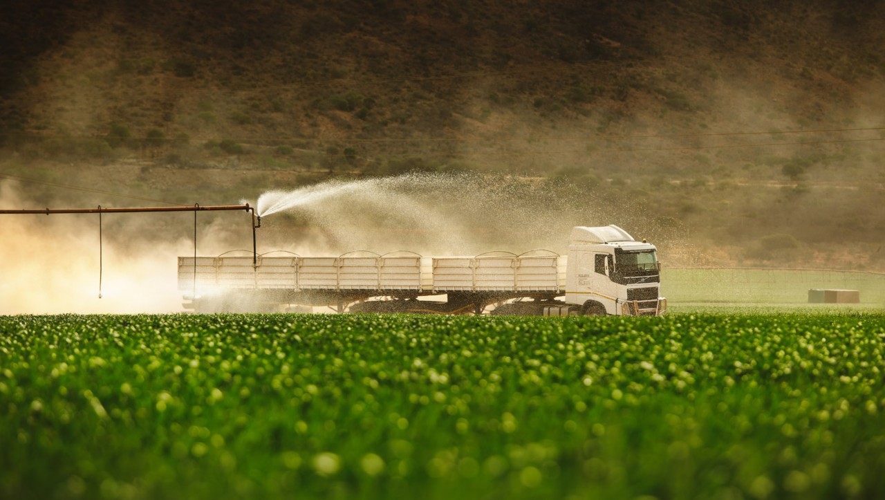 Volvo FH ohittaa vihreän niityn, jota kastellaan sprinklerillä